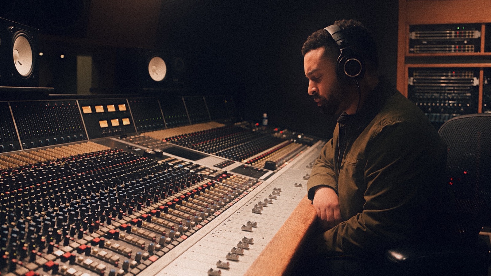 Luis Canción wearing headphones at an analog mixing console in the studio.